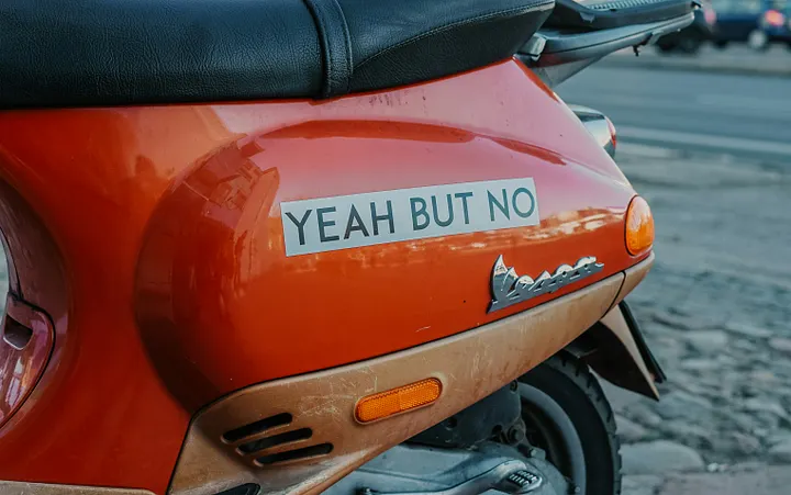 Red motorcycle with sticker that reads "Yeah but no"