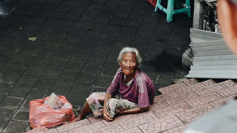 Poor old woman sitting on steps 