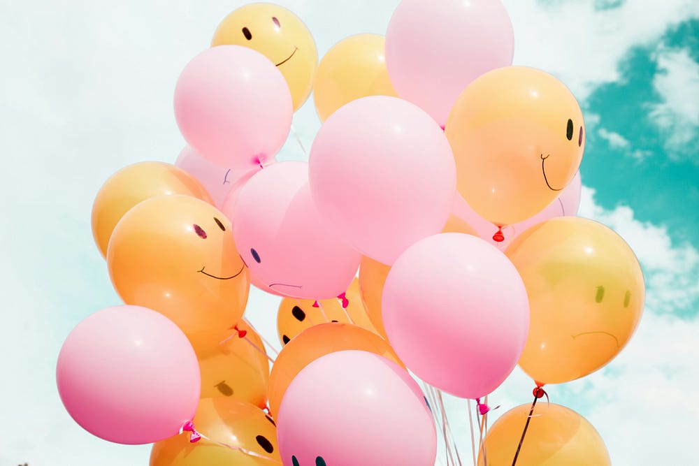 A bunch of happy faced balloons in pink and orange color