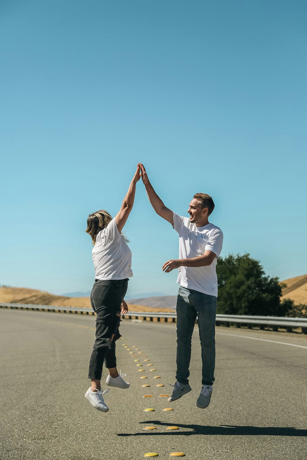A man and a woman high five in the middle of the road
