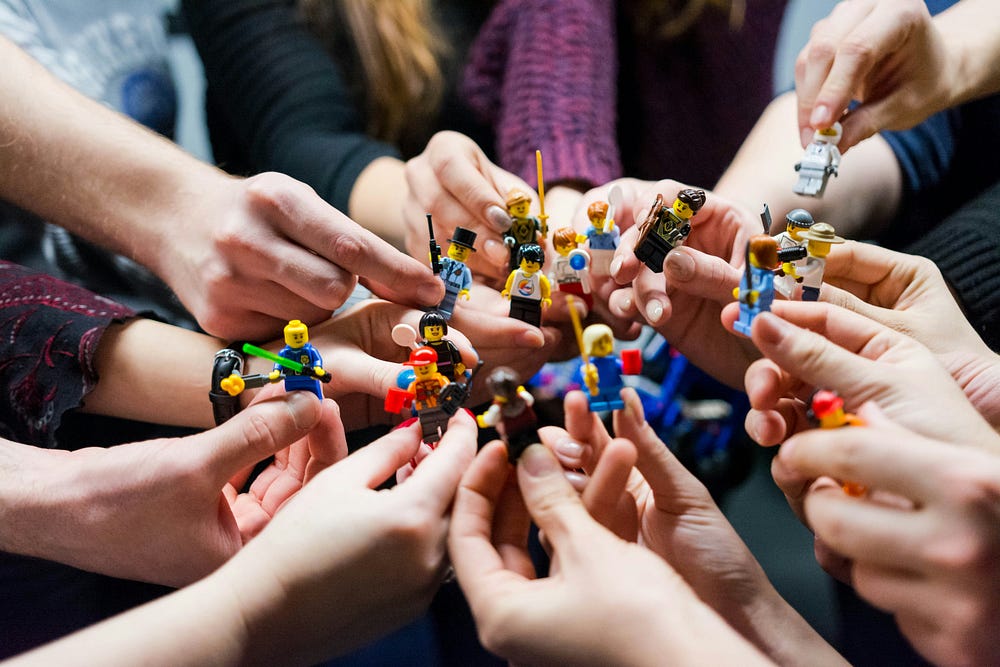 Many hands holding Lego figures