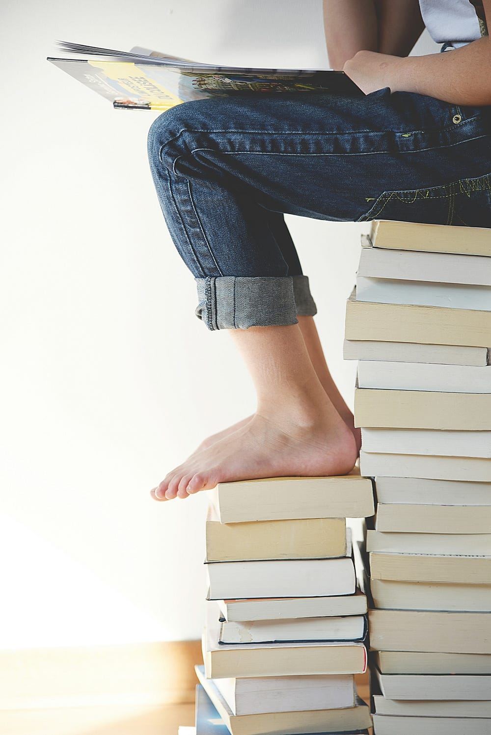 A pile of books and a child sitting on it reading a book