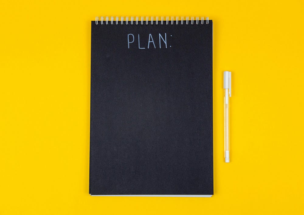 A yellowbackground and a black board that says on top PLAN