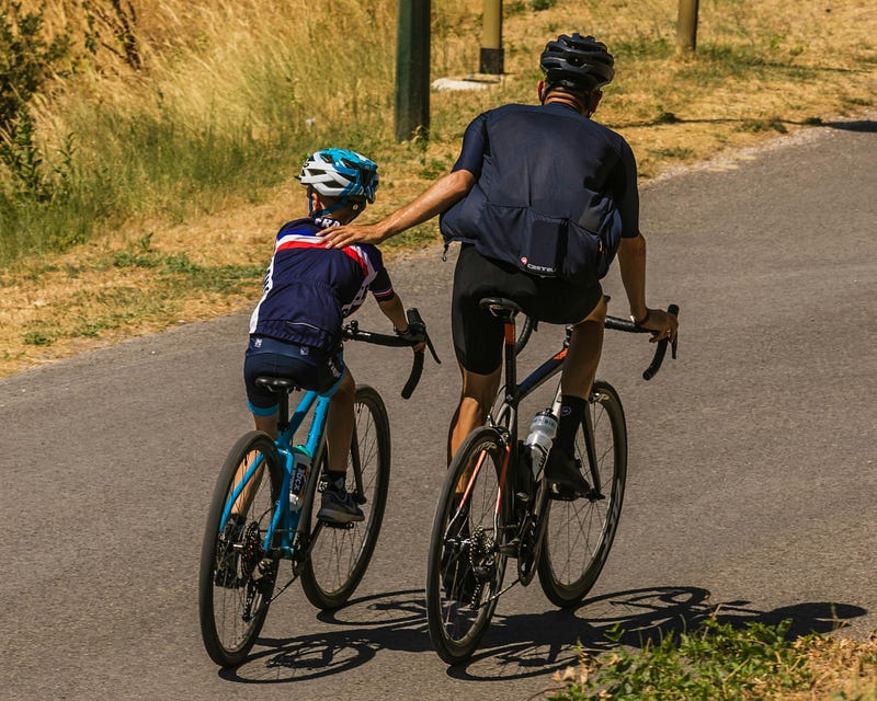 A father and a son biking along side each other 