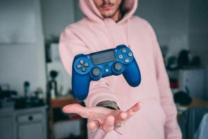 Boy with a pink shirt throwing a controller up in his hands