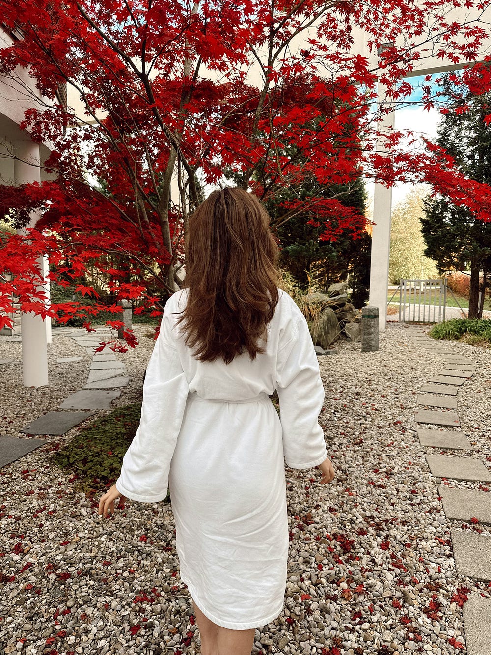 Woman in a bathrobe in front of a beautiful tree with red flowers